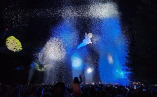 'Place des Anges' written and directed by Pierrot Bidon and Stéphane Girard at WOMADelaide festival 2023. Photo: Grant Hancock. A balloon angle floats in the night sky filled with confetti and a standing audience.