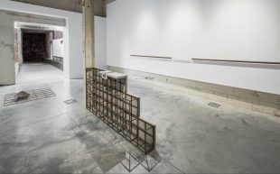 'Nicholas Burridge: Built Geologies' installation view at Canberra Glassworks. Photo: Brenton McGeachie. Exhibition in an industrial space with concrete floor and white walls. A metal structure is at the centre, shaped like a narrow staircase.