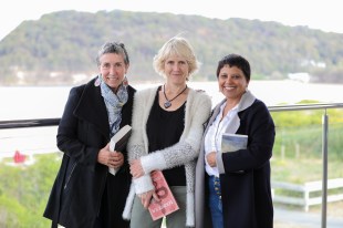 Central Coast free reading program. Image is three middle-aged women holding books, standing on a balcony overlooking greenery, a lake and a hill.