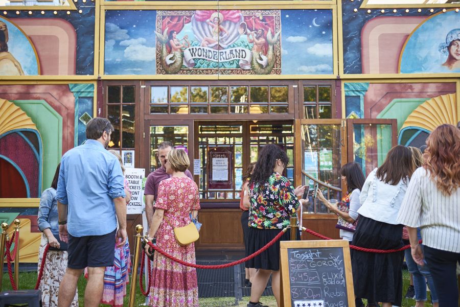 Arts ticket sales: a group of people mingling outside a fringe festival art venue.