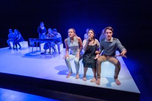 theatre-makers. Actors sitting on white boxes on a black box stage, three facing front, more behind.