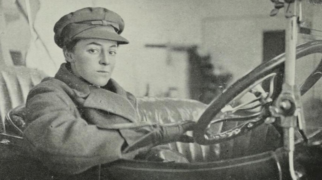 State Library Victoria. The Chapters. Image is a woman in driver's gear at the steering wheel of an old car in a black and white shot.