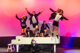 Teenage performers in tuxedos and shorts jump out of a white piano in Tempo by the Flying Fruit Fly Circus at Art Centre Melbourne.