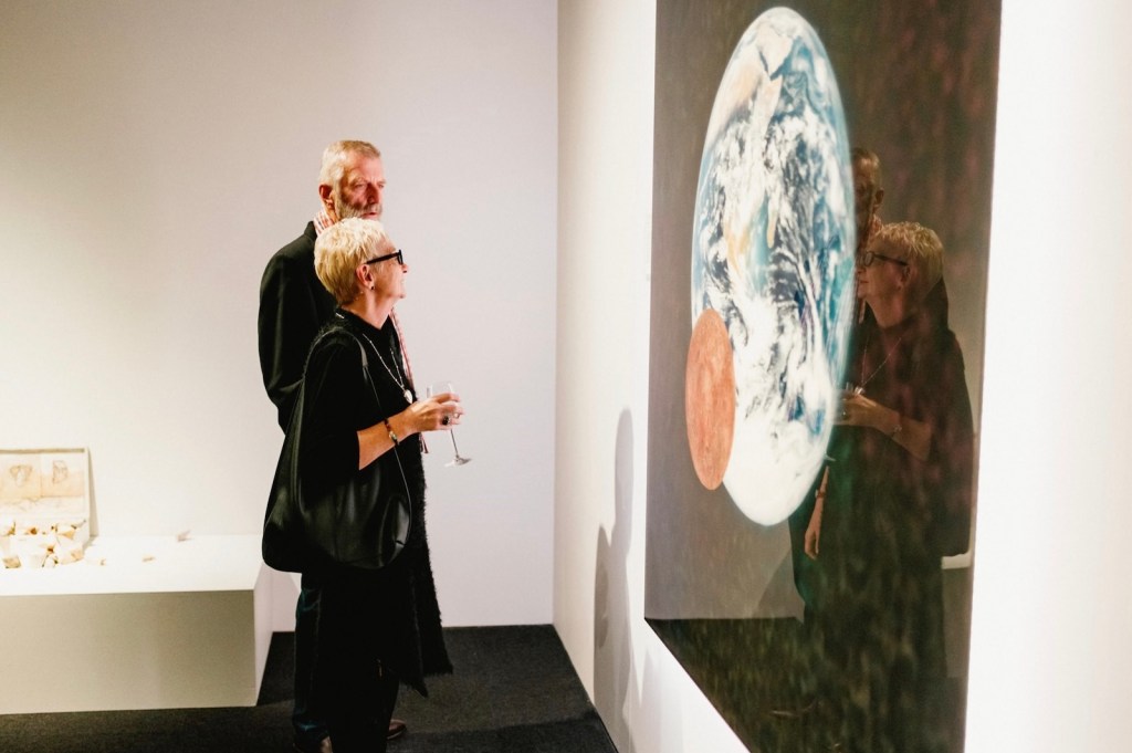 Elderly couple dressed in black looking at artwork in a gallery