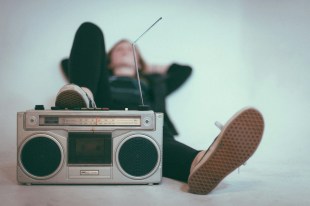 Photo: Eric Nopanen, Unsplash. Woman lying on the ground near grey radio.