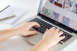 Arts news. Hands typing on laptop keyboard.