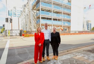 Three people stand outside new museum construction. Powerhouse.