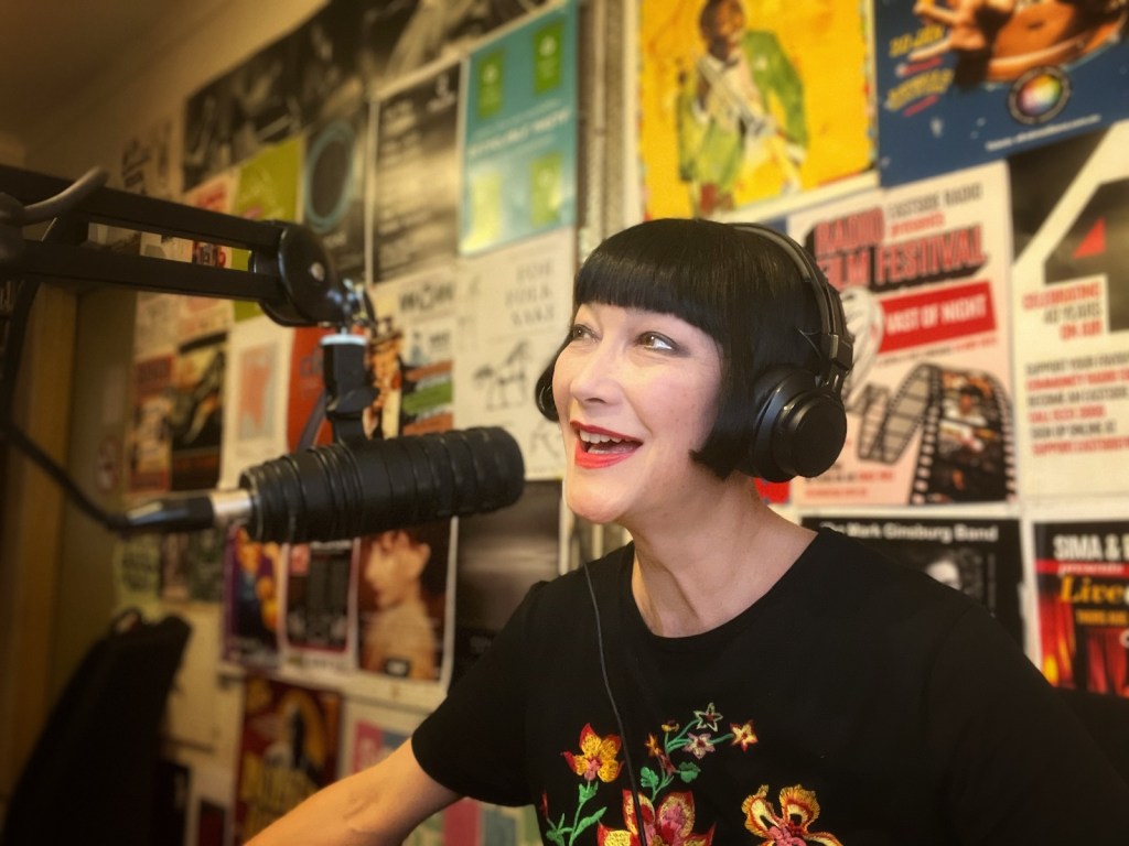 Woman wearing black t-shirt in radio studio. Claudia Chan Shaw.