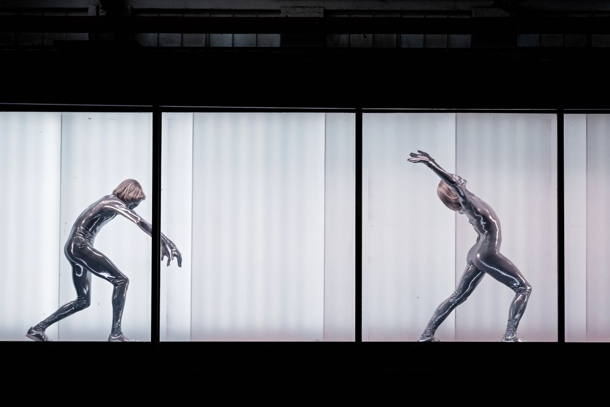 Future Cargo. Two figures in silver bodysuits moving across a panel.