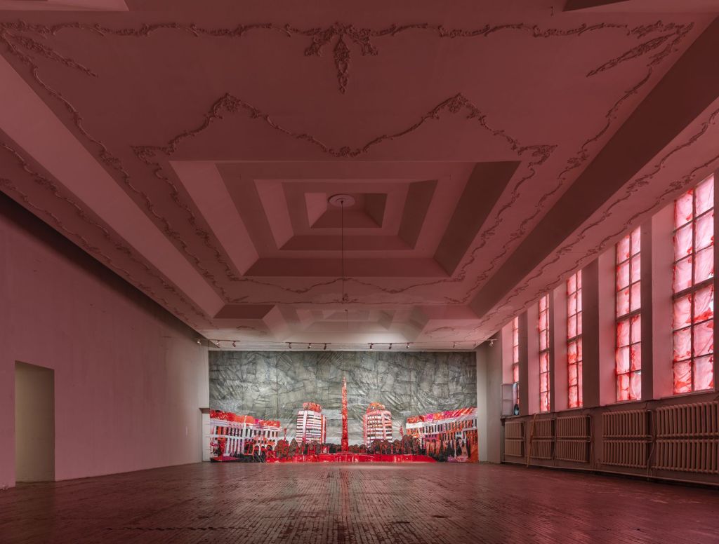 Saule Suleimenova, ‘We Are Ordinary People,’ installation view. Photo: Supplied. A black and red city scape made out of plastic bags is displayed in a spacious gallery with no people. The room is washed in a red hue, with red plastic bags also covering the windows. 