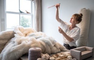 Design News. Meindertsma. Woman in white t-shirt inspecting wool samples.