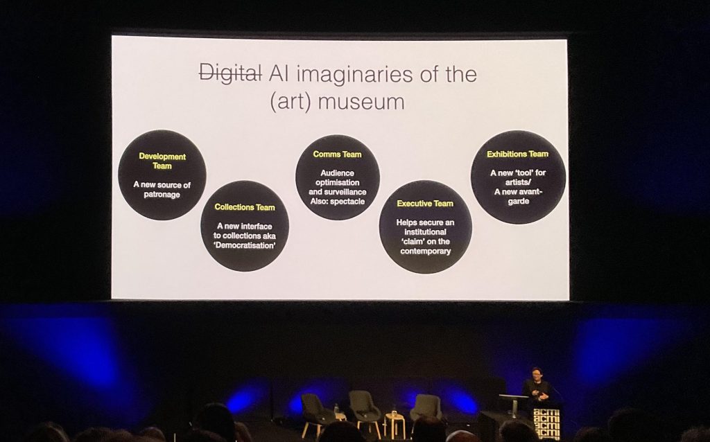 Katrina Sluis presenting 'Looking at the Machine' at ACMI Future of Arts, Culture & Technology Symposium 2024. Photo: ArtsHub. A presentation slide on stage outlining the AI imaginaries of the art museum. The content of the slide is discussed in the article.