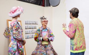 Powerhouse Residency open for applications. L-R: Stefania Gertis, Jenny Kee, Iordanes Spyridon Gogos. Photo: Zan Wimberley. Three peopel wearing colourful sculptural garments standing in a studio space with white walls. The garments have dreamy tones of pink, purple and bnlue, with sculptural bits poking out like patterned paper cuts.