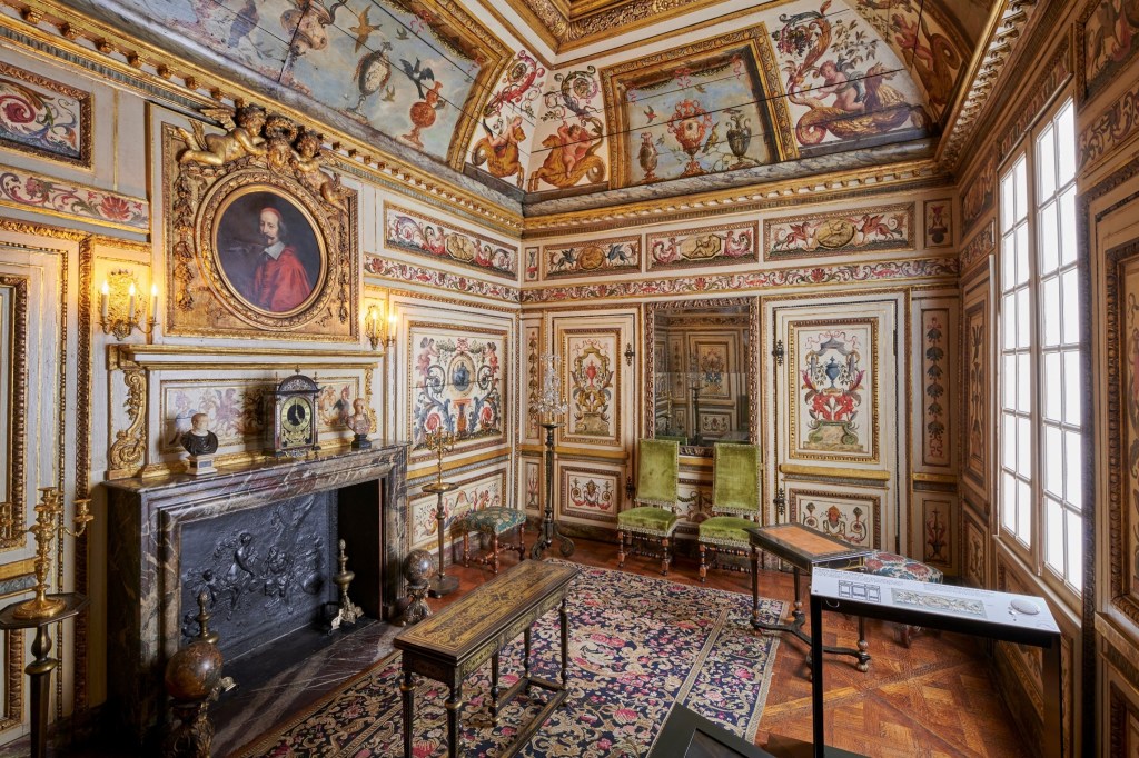 Musée Carnavalet – Cabinet Colbert de Villacerf. Photo: Supplied. A grand room inside the Musée Carnavalet with extravagant gold furnishing and artworks painted on every surface, from the walls to the ceiling. The space also features vintage furniture and a large portrait of a man in a red cloak above the mantelpiece. 