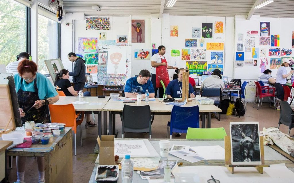 Celebrate Arts Project Australia's 50th anniversary at the Northcote Studio Open Day. Photo: Supplied. APA artists at work in the studio. Artworks and material can be seen on walls and laid out on tables, with around 10 people inside the studio.