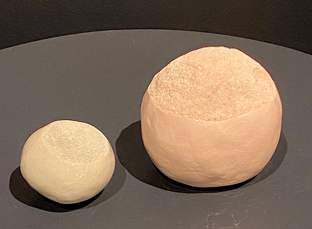 Pair of ceramic, textured orb sculptures in gallery setting. Danish Quapoor