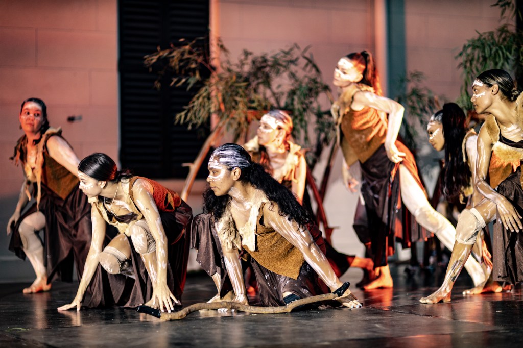Jannawi Dance Clan to perform at Powerhouse Castle Hill opening weekend on 23 March. Photo: Supplied. A group of seven female dancers in ceremonial First Nations outfit and paint on their faces and bodies, crouching or lunging on the stage. 