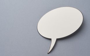 Photo: eskay lim, Unsplash. Photo of a cut out white speech bubble on a grey background.