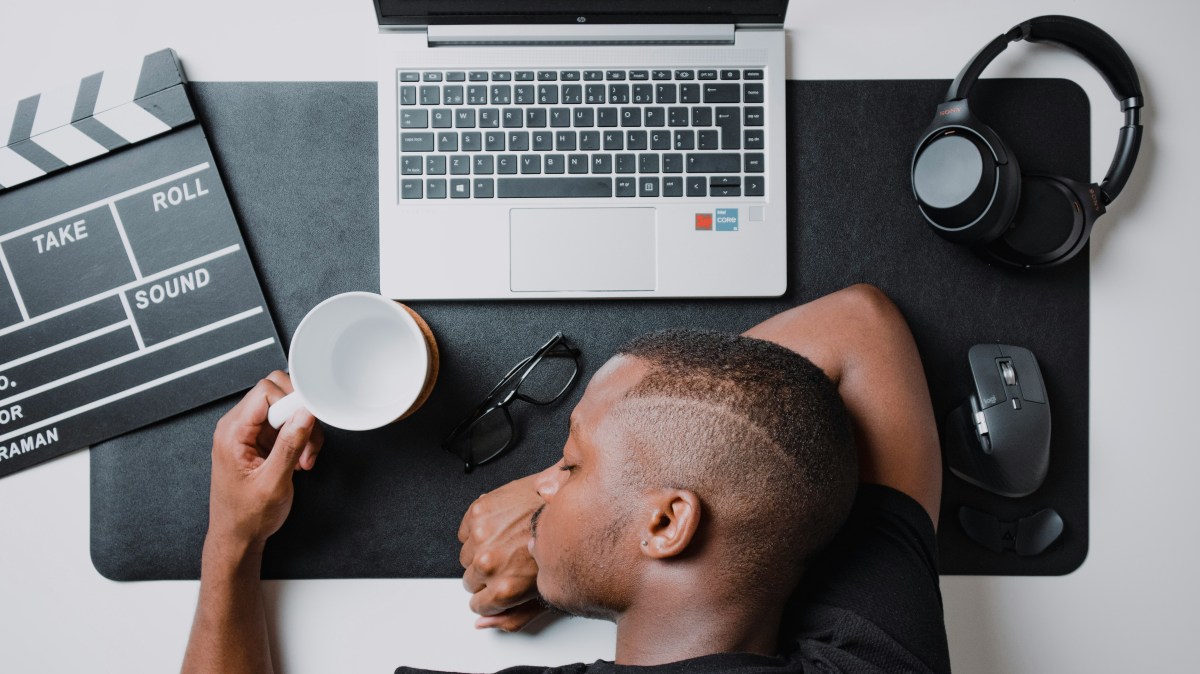 A young film editor collapses at his desk from burnout on multiple projects.