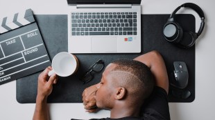 A young film editor collapses at his desk from burnout on multiple projects.