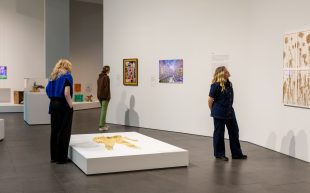 ‘Top Arts 2024’, installation view at The Ian Potter Centre: NGV Australia. Photo: Kate Shanasy. Three people looking at artwork inside a spacious gallery with white walls and grey concrete floor.