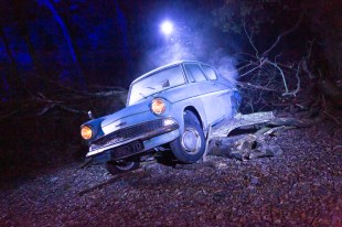 Harry Potter: A Forbidden Forest Experience. Image is an old Ford Anglia with its lights on crashed in a forest and spotlit from above.