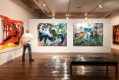 Man looking at abstract colourful paintings in gallery. Dale Frank