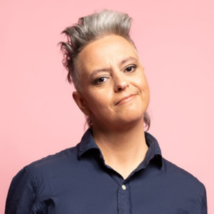 Headshot of a middle aged smiling woman with head tilted to the left. She has short sticking up grey hair and is wearing a dark blue collar shirt. Geraldine Hickey.