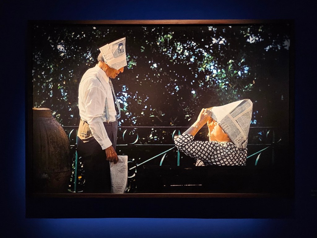 Work from ‘Through the playful eyes of Elliot Erwitt’, installation view at Fotografiska Shanghai. Photo: ArtsHub. The photo depicts an elderly couple wearing paper boat hats in a park environment.