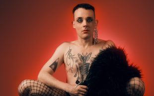 Jessi Ryan: Functional Bottom. Image is a topless young performer in fishnet stockings sitting on their haunches with a fur coat draped across their knee. They have heavy make-up and chest and arm tattoos.