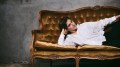 Sarah Keyworth. My Eyes Are Up Here. Image is a white non-binary person in a white shirt, leaning on an elbow and lying on a padded brown velvet couch.