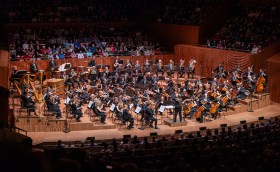The full Sydney Symphony Orchestra in concert, as viewed from the dress circle of a concert hall.