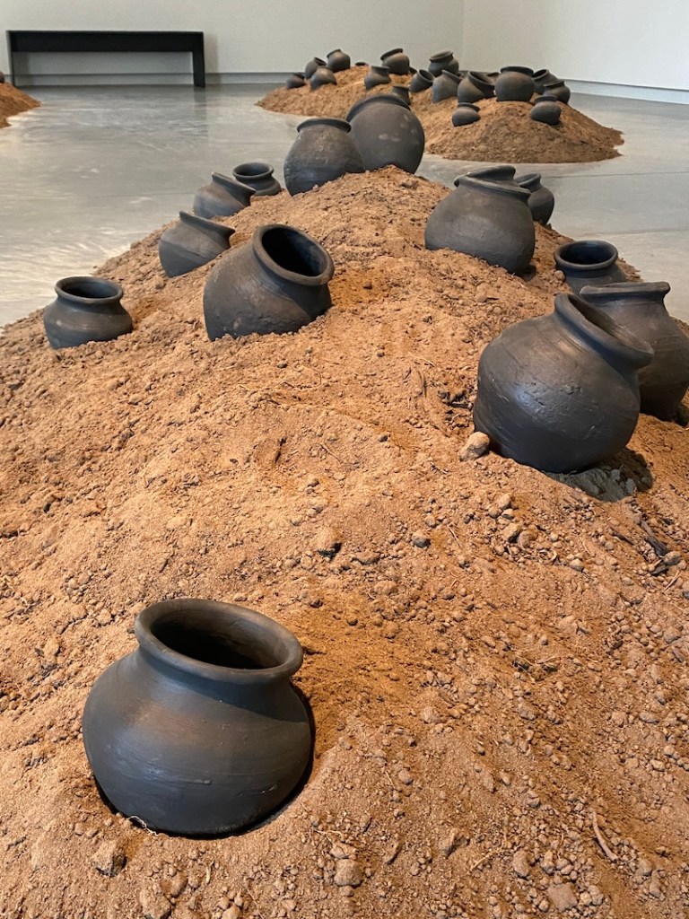 Soil with black earthenware pots in gallery setting.