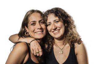 Portraits: a photographic portrait of two sisters pictured while looking into the camera while one has her arm around the other, set against a white background.