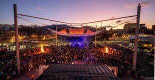 An aerial view taken at dusk of a large crowd gathered outdoors preparing to sing together as part of The Big Sing at Festival of Voices.