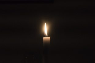 A lit candle against a black backdrop.