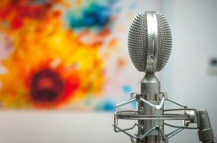 microphone with colourful painting in background. Arts news.
