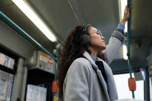 A woman wearing headphones standing on a train.