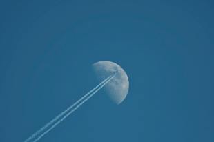 Aeroplane contrails across a blue sky with a half-full moon visible in the background. Arts sector appointments.