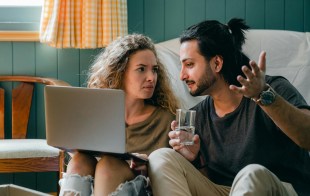 Man and woman sitting on floor looking at computer