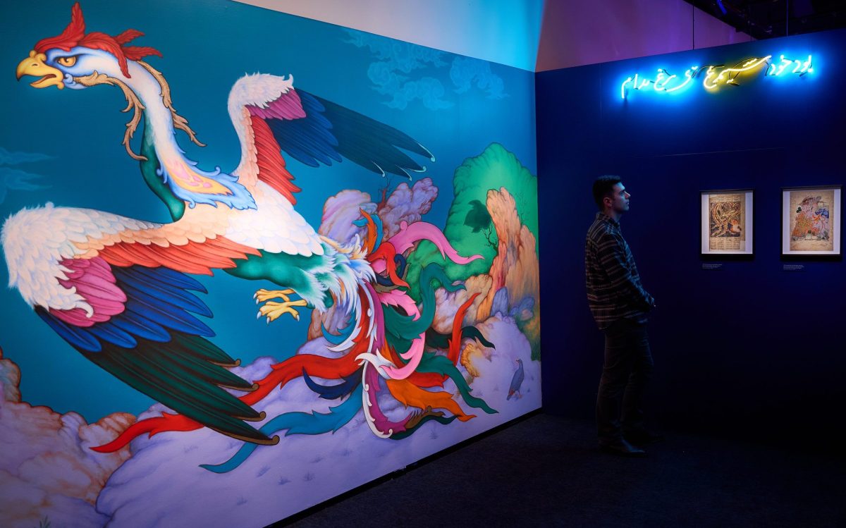 in a gallery, huge mural of a colourful flying bird with big black tipped wings.