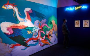 in a gallery, huge mural of a colourful flying bird with big black tipped wings.