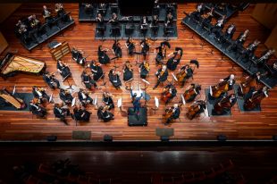 A bird's-eye view of the Canberra Symphony Orchestra in concert, taken directly above the stage and looking straight down.