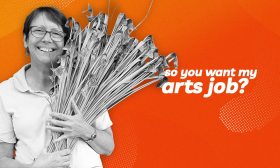 So you want my arts job. A woman holding an armful of basketry materials smiles at the camera.