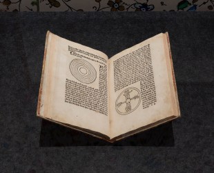 World of the Book. Image is an ancient book, printed in the 15th century, lying open.