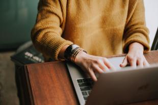 pitching tips. Image is a headless person in a tan jumper sitting at a laptop computer typing.