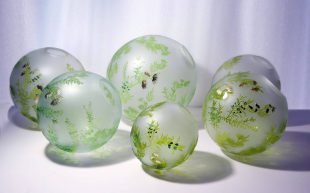 Waterhouse Natural Science Art Prize People's Choice winning work 'Six is the loneliest number' by Jessica Murtagh. Photo: Supplied. Glass globes with intricately painted leaves in green, black and gold.