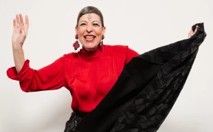 Natalie Gamsu. Photo: Marija Ivkovic. A person smiling brightly wearing a red top and black skirt, which she is holding in her hand.