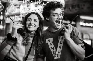 2023 AFTRS Master of Arts Screen: Producing graduates, L-R: Neisha Dallamora and Denis Curnow. Photo: Flore Vallery-Radot. A black and white photo of Neisha and Denis on set, posing at the camera while holding walkie talkies.