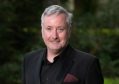 ArtsHub's Performing Arts Editor Richard Watts OAM. A grey-haired, fair-skinned man in late middle age smiles at the camera. He is wearing a black jacket over a black business shirt; a dark red pocket handkerchief protrudes from his jacket's breast pocket.